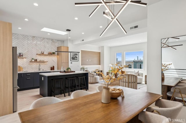 dining room with recessed lighting, light wood finished floors, and bar with sink