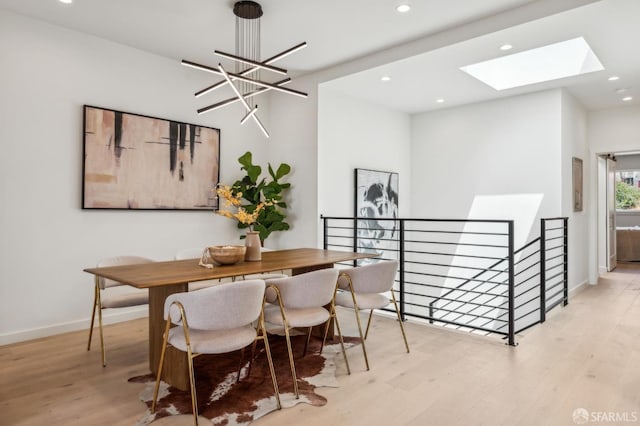 dining area featuring wood finished floors, a skylight, recessed lighting, baseboards, and a chandelier