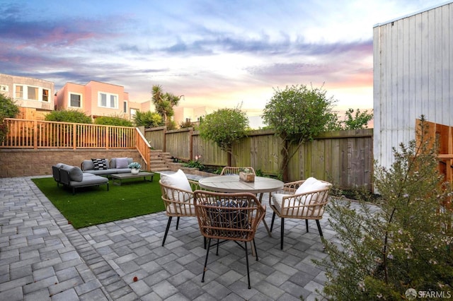 patio terrace at dusk with an outdoor hangout area, a fenced backyard, and outdoor dining space