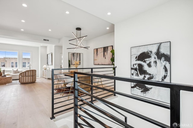 hall with an upstairs landing, recessed lighting, light wood-type flooring, and a chandelier
