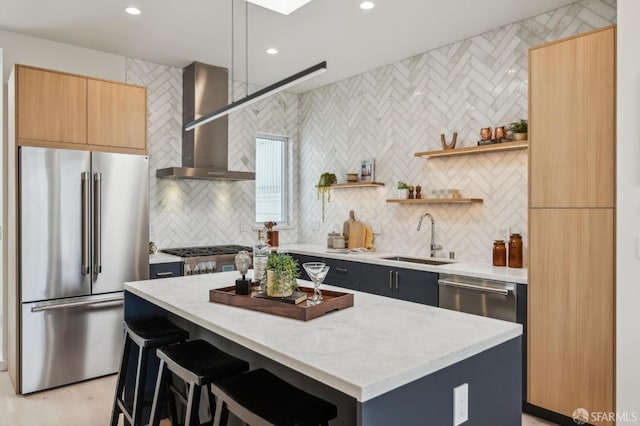 kitchen featuring stainless steel appliances, a sink, wall chimney exhaust hood, a center island, and decorative backsplash