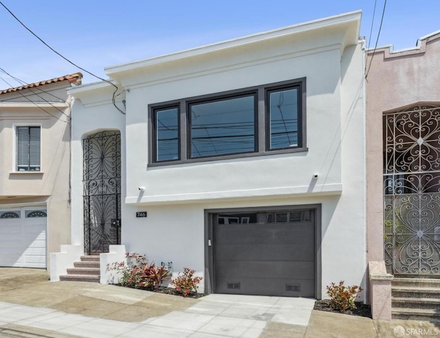 view of front facade with an attached garage, stucco siding, and driveway