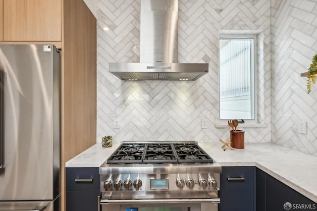 kitchen featuring stainless steel appliances, wall chimney exhaust hood, decorative backsplash, and light stone counters
