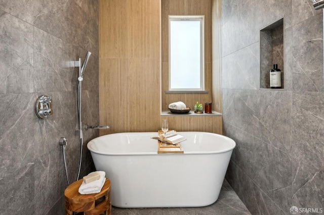 bathroom featuring a soaking tub, tile walls, and a tile shower