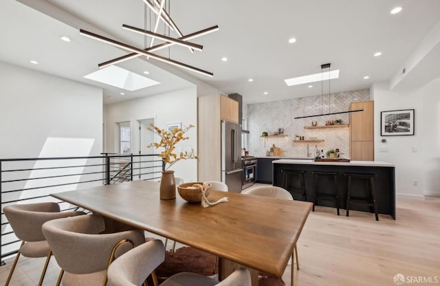 dining area with a skylight, recessed lighting, and light wood finished floors