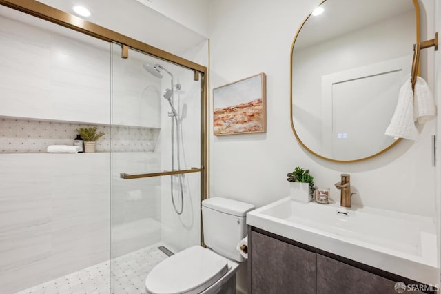 full bathroom featuring a shower stall, toilet, and vanity