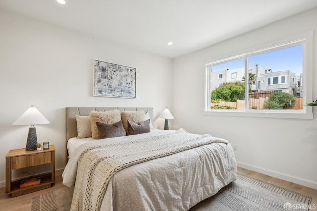 bedroom with baseboards, wood finished floors, and recessed lighting