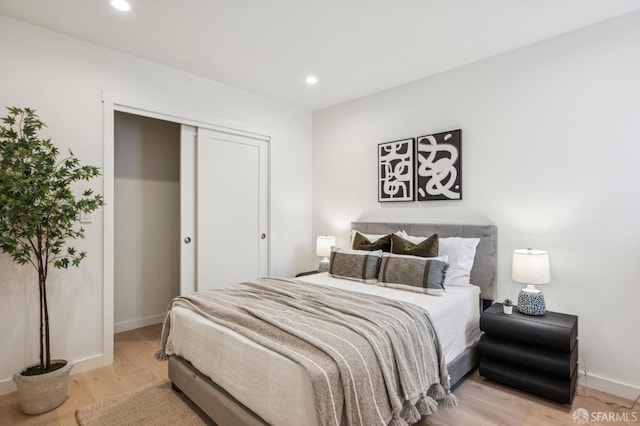bedroom featuring light wood-style flooring, recessed lighting, baseboards, and a closet