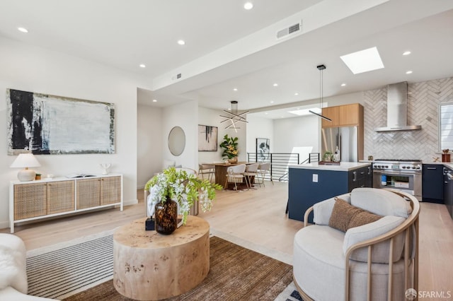 living room with recessed lighting, light wood-style floors, and a skylight