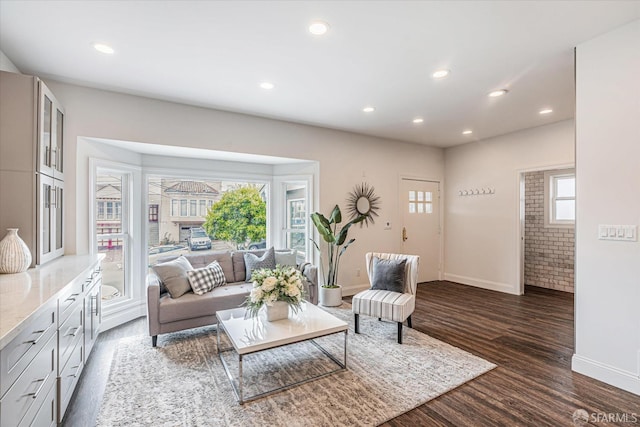 living room featuring brick wall, a healthy amount of sunlight, and dark wood-type flooring