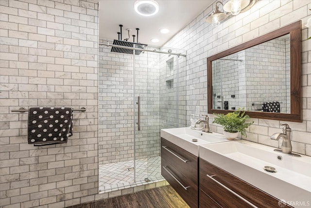 bathroom with tile walls, vanity, wood-type flooring, and a shower with door