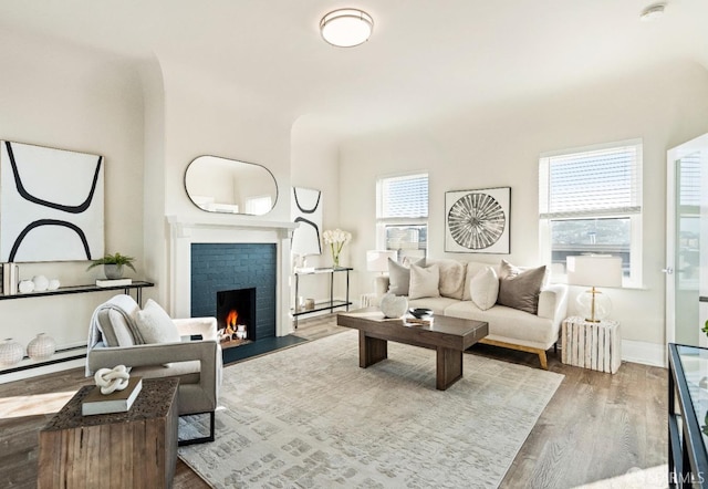 living room with a baseboard heating unit, hardwood / wood-style flooring, a brick fireplace, and a healthy amount of sunlight