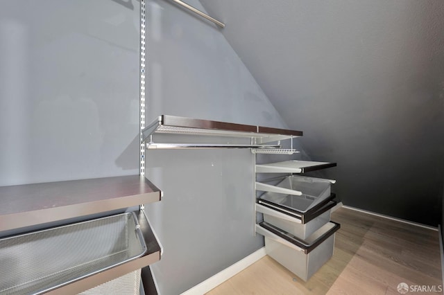 stairs featuring wood finished floors, vaulted ceiling, pet washing area, and baseboards