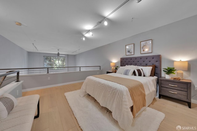 bedroom featuring light wood-style floors, baseboards, and track lighting