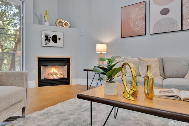 living area featuring a glass covered fireplace and baseboards