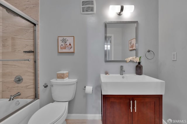 full bath featuring toilet, vanity, combined bath / shower with glass door, and baseboards