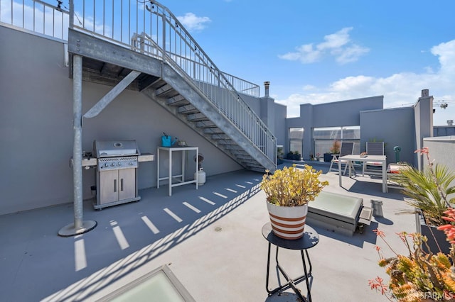 view of patio with stairway and a grill