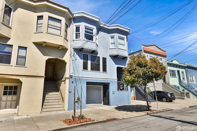 1258 York St, San Francisco, CA 94110 - view of front facade with stucco siding, stairway, an attached garage, and driveway