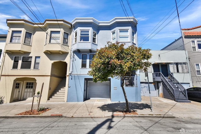 1258 York St, San Francisco, CA 94110 - view of front of home with stairway, a garage, stucco siding, and driveway