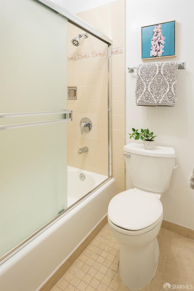bathroom featuring tile patterned floors, toilet, baseboards, and bath / shower combo with glass door