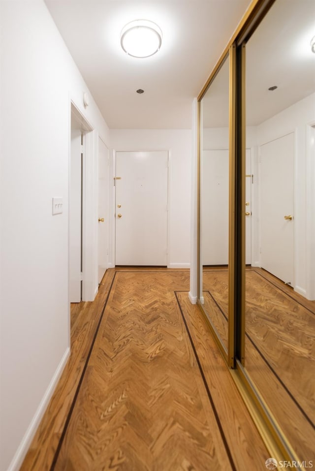hallway featuring baseboards and parquet floors