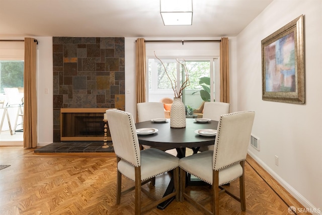 dining room with a tiled fireplace, baseboards, and visible vents