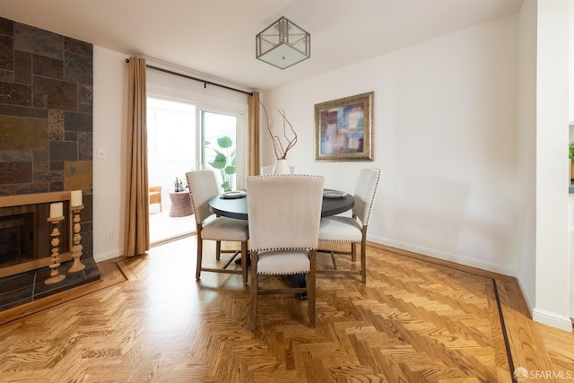 dining area featuring a tiled fireplace and baseboards