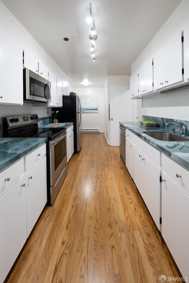 kitchen with appliances with stainless steel finishes, a sink, white cabinetry, and dark countertops