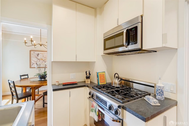 2201 Sacramento St Unit 404, San Francisco, CA 94115 - kitchen featuring dark countertops, appliances with stainless steel finishes, a chandelier, white cabinetry, and light wood-type flooring