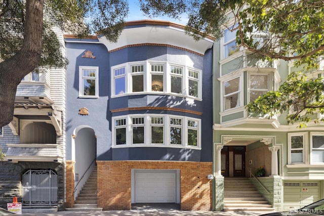 1980-1982 Fell St, San Francisco, CA 94117 - view of front facade featuring stucco siding, a garage, stairway, and brick siding