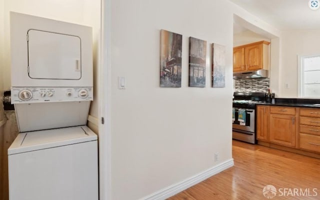 laundry area featuring stacked washer and dryer and light hardwood / wood-style floors