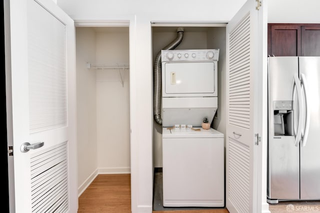 laundry room with light hardwood / wood-style floors and stacked washer / dryer