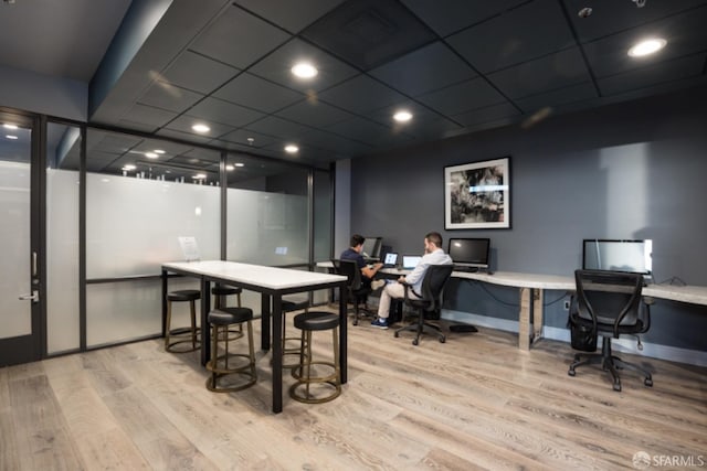 dining area featuring a paneled ceiling, light hardwood / wood-style flooring, and built in desk