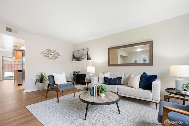 living room with light wood-style floors, baseboards, and visible vents