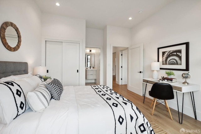 bedroom featuring light hardwood / wood-style floors, a closet, and ensuite bath