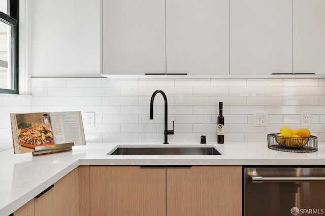 kitchen with light stone countertops, sink, dishwasher, decorative backsplash, and white cabinets