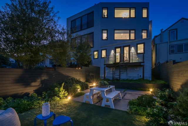 back house at twilight with a patio area