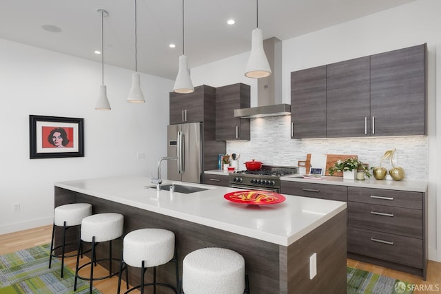 kitchen featuring high end appliances, an island with sink, sink, and hanging light fixtures