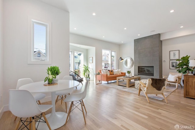 dining room with a tiled fireplace and light hardwood / wood-style flooring