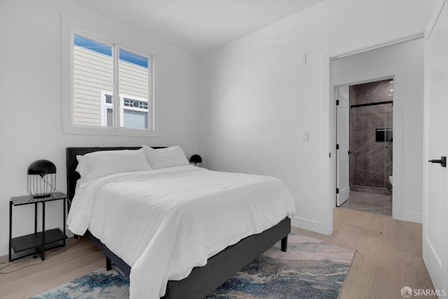 bedroom with ensuite bathroom and light hardwood / wood-style flooring