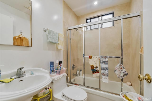 full bath featuring a sink, combined bath / shower with glass door, and toilet