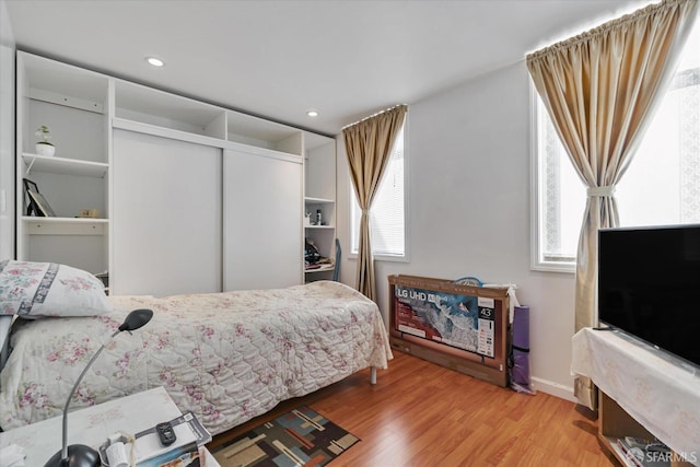 bedroom with baseboards, a closet, recessed lighting, and wood finished floors