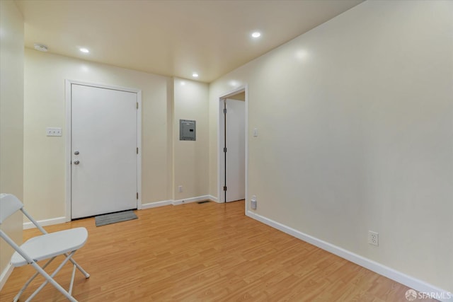 foyer featuring baseboards, recessed lighting, light wood finished floors, and electric panel