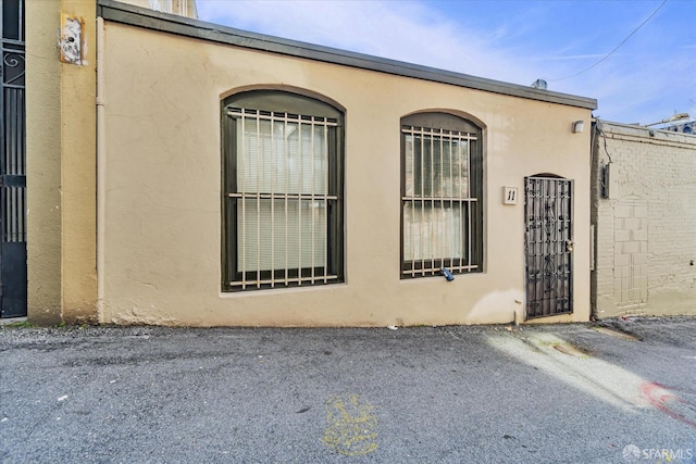 view of side of property with a gate and stucco siding