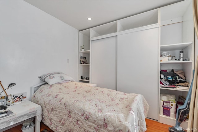 bedroom with wood finished floors and a closet
