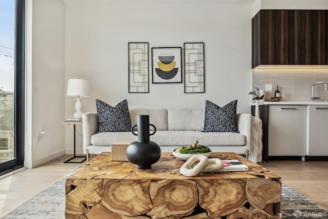 living room featuring sink, a healthy amount of sunlight, and light hardwood / wood-style flooring