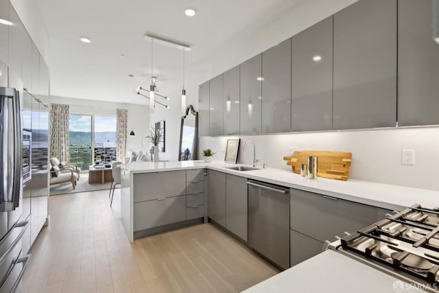 kitchen featuring gray cabinetry, appliances with stainless steel finishes, a sink, modern cabinets, and open floor plan