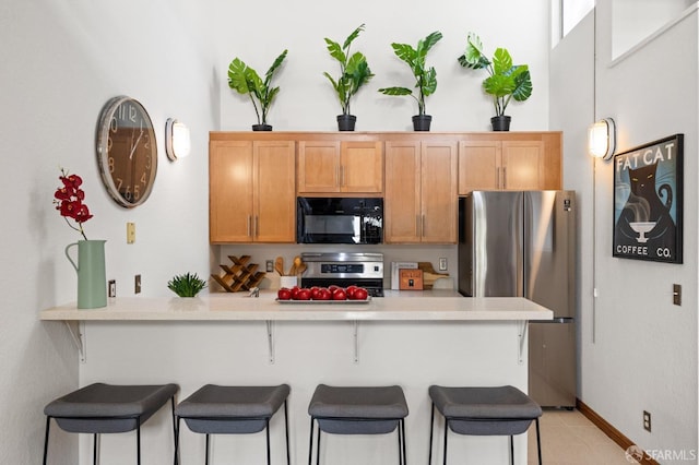 kitchen featuring kitchen peninsula, appliances with stainless steel finishes, and a breakfast bar area