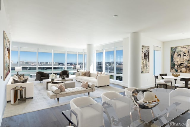 living area with a city view, a wall of windows, visible vents, and wood finished floors