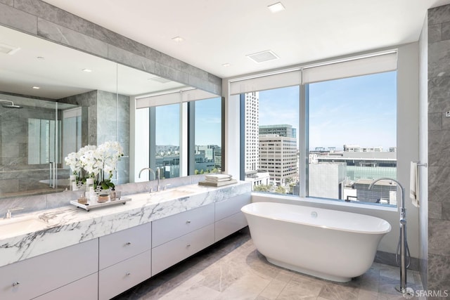 bathroom featuring plenty of natural light, a shower stall, a view of city, and double vanity